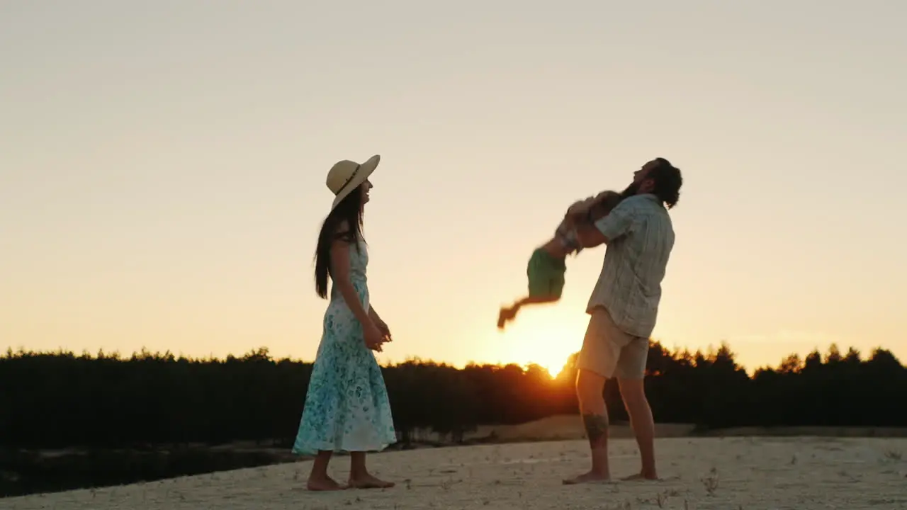 Young Happy Family Playing With His Son At Sunset Father Tossing Baby