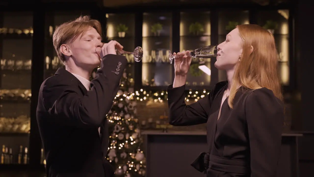 A Woman And A Man Dressed In Elegant Clothes Toast With A Glass Of Champagne And Take A Sip At The New Year's Party