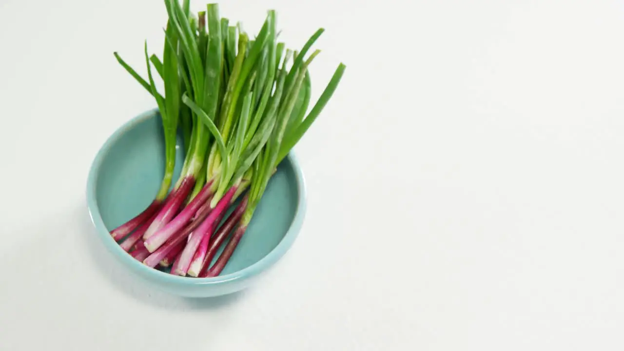 Spring onion in bowl placed on white surface 4K 4k