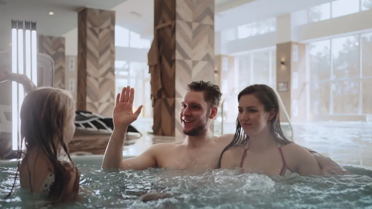 spouses are relaxing in jacuzzi in modern spa center children are playing near happy family weekend