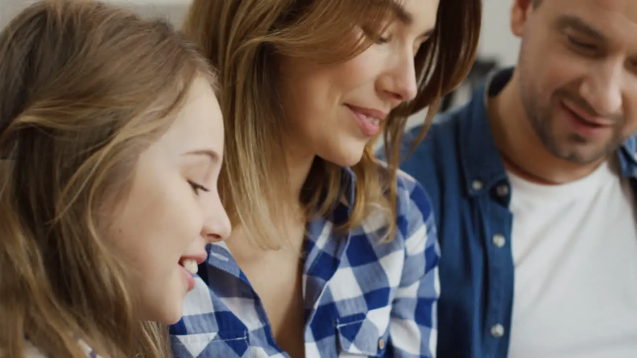 Close Up Of The Nice Happy Family Of Parents And Two Kids Sitting Close To Each Other And Looking At Something With Smiles