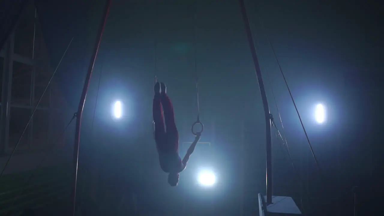 a Still shot of a guy working out on the still rings a gymnastics apparatus that is extremely hard in slow motion 180 fps