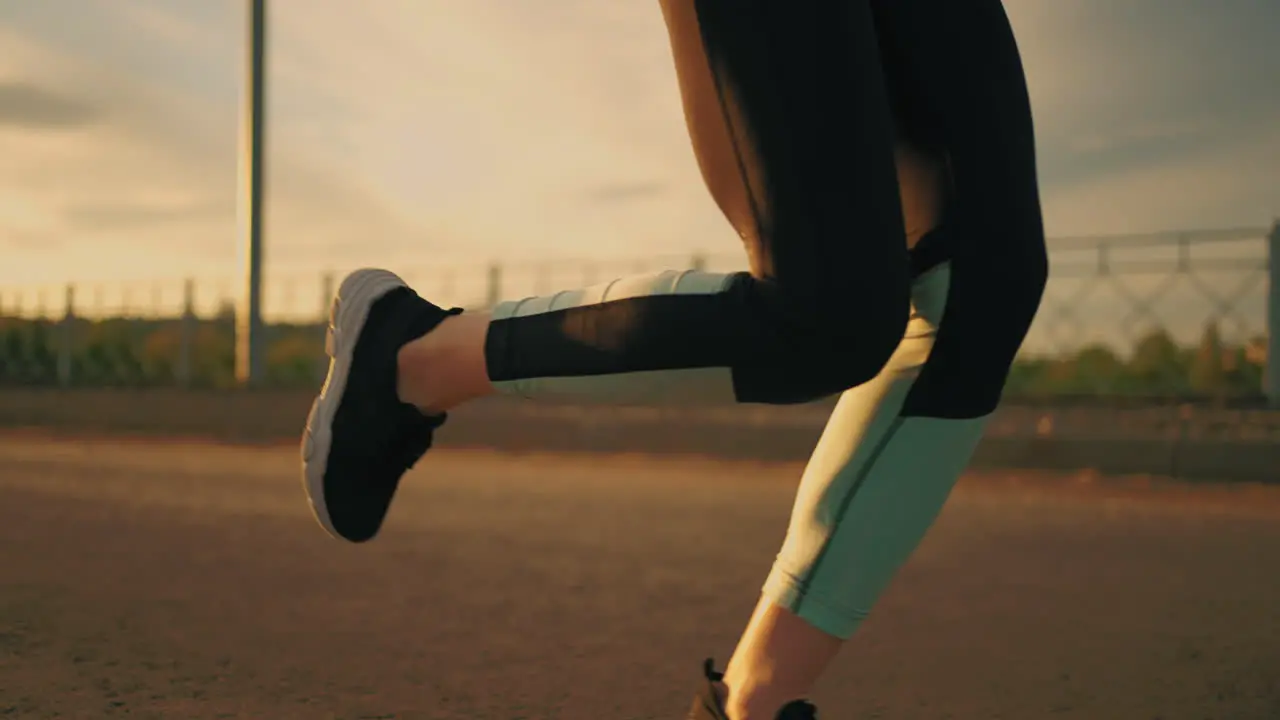 athletic woman is running outside in sunset or evening close up of body dressed in sportswear