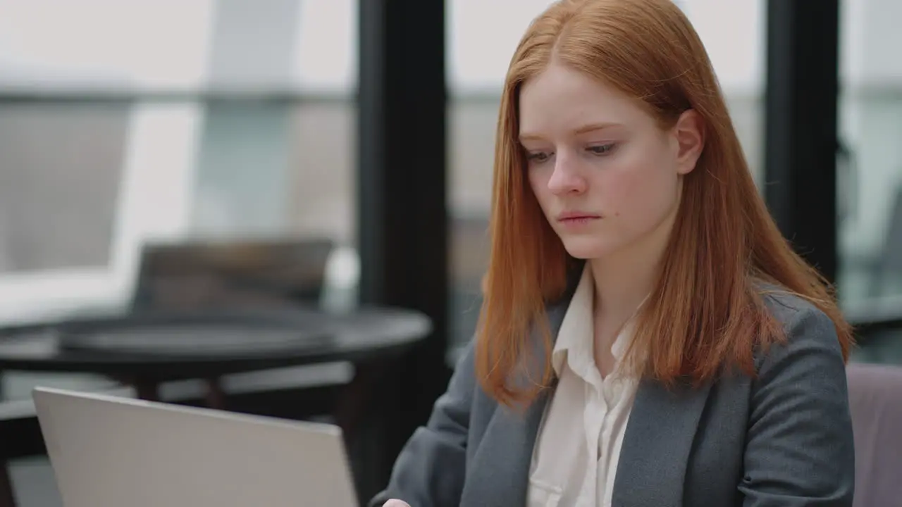 young businesswoman in grey jacket is working with notebook in cafe or restaurant checking emails and reports