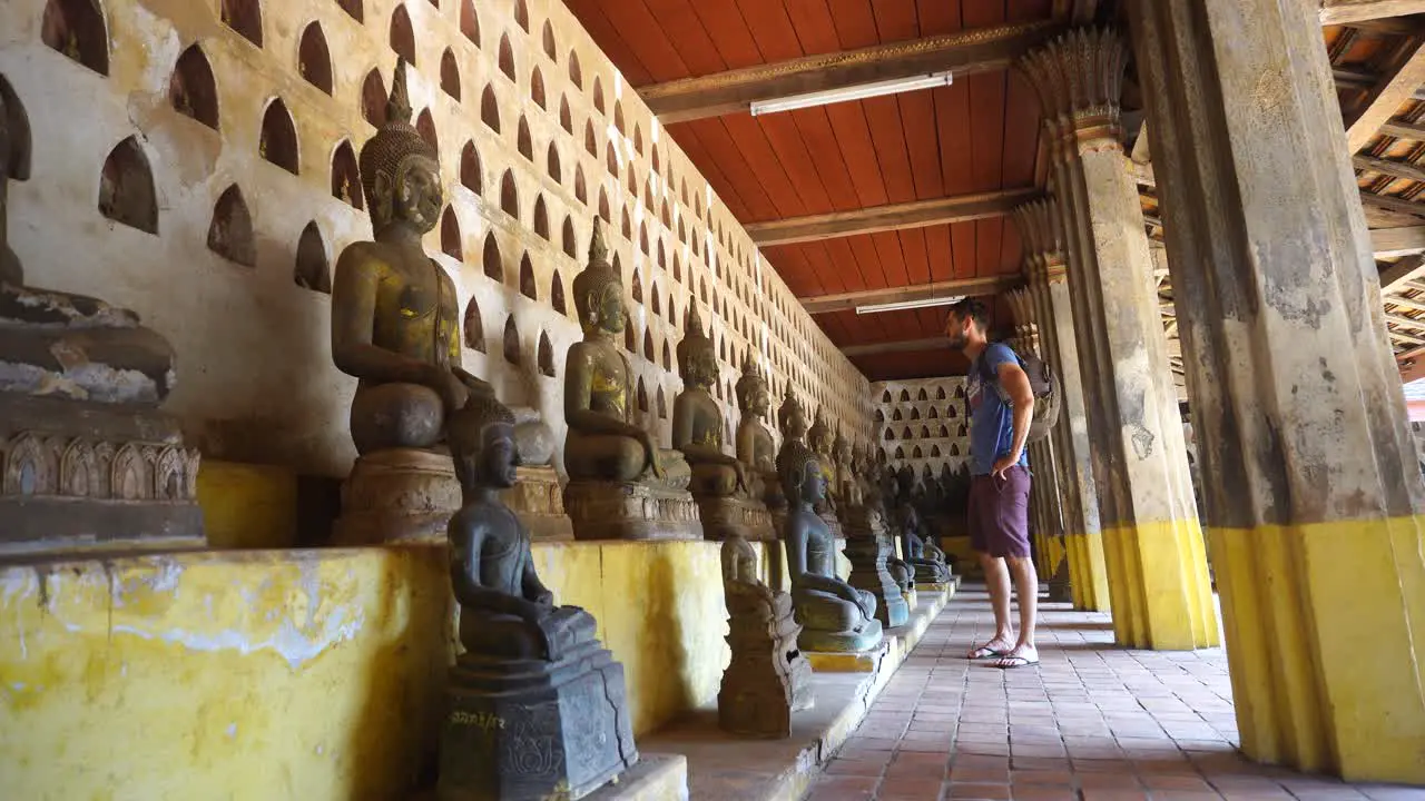 Male Tourist Looking At Rows Of Buddha Statues At Wat Si Saket In Vientianne