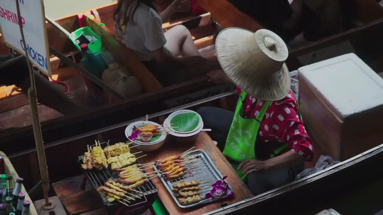 Down to zoom out shot Fried Shrimp and Chicken bbq vendor in Thailand floating market cold beverages at the rear of the boat