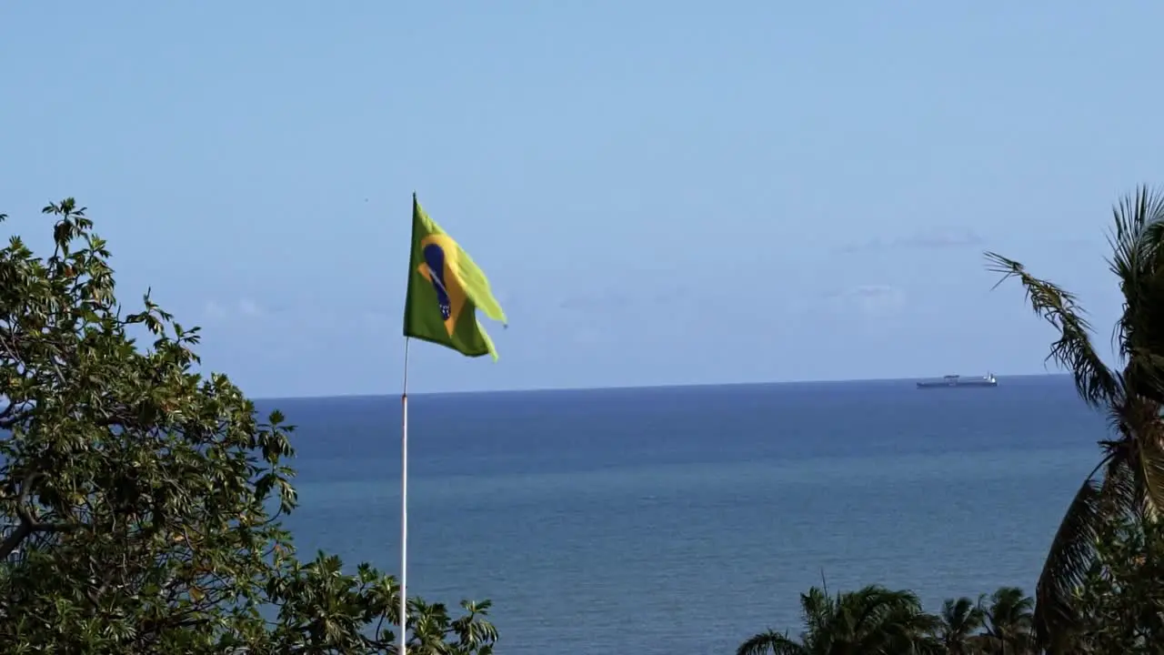 Brazil flag close-up waving in the wind in 120fps slow motion with the vast ocean in the background in the historic city of Olinda in Pernambuco Brazil on a warm sunny clear summer day