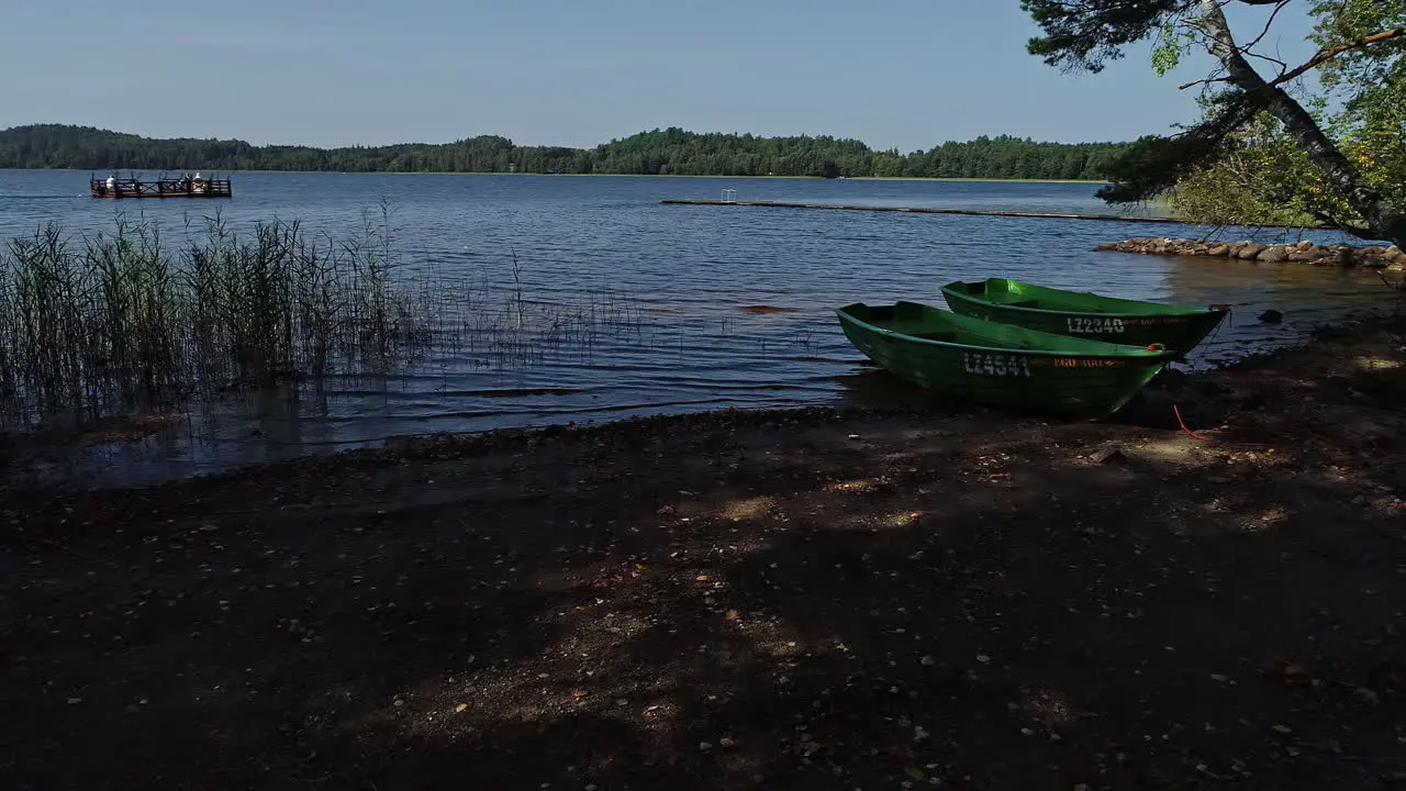 Smooth shot of boats on a costline an people sailing on platform with beautiful ripples in the lake in the middle of a forest