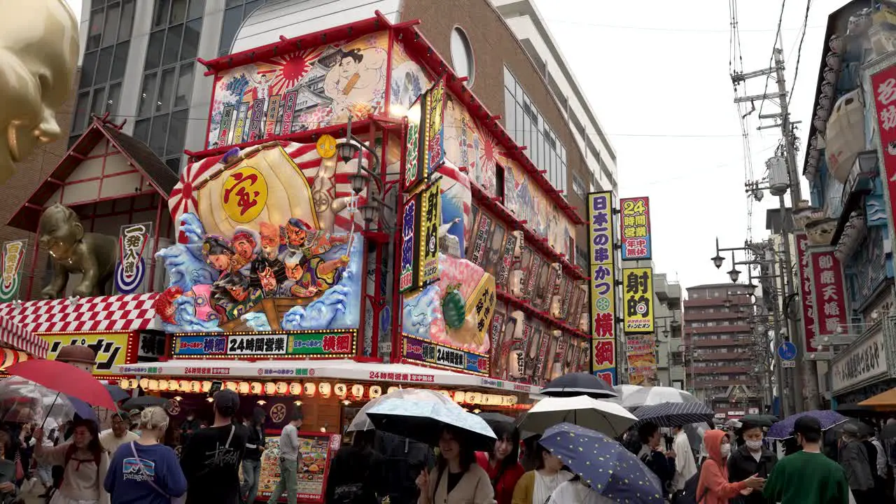 Busy Crowds With Umbrellas Walking Through Shinsekai Area On Rainy Day