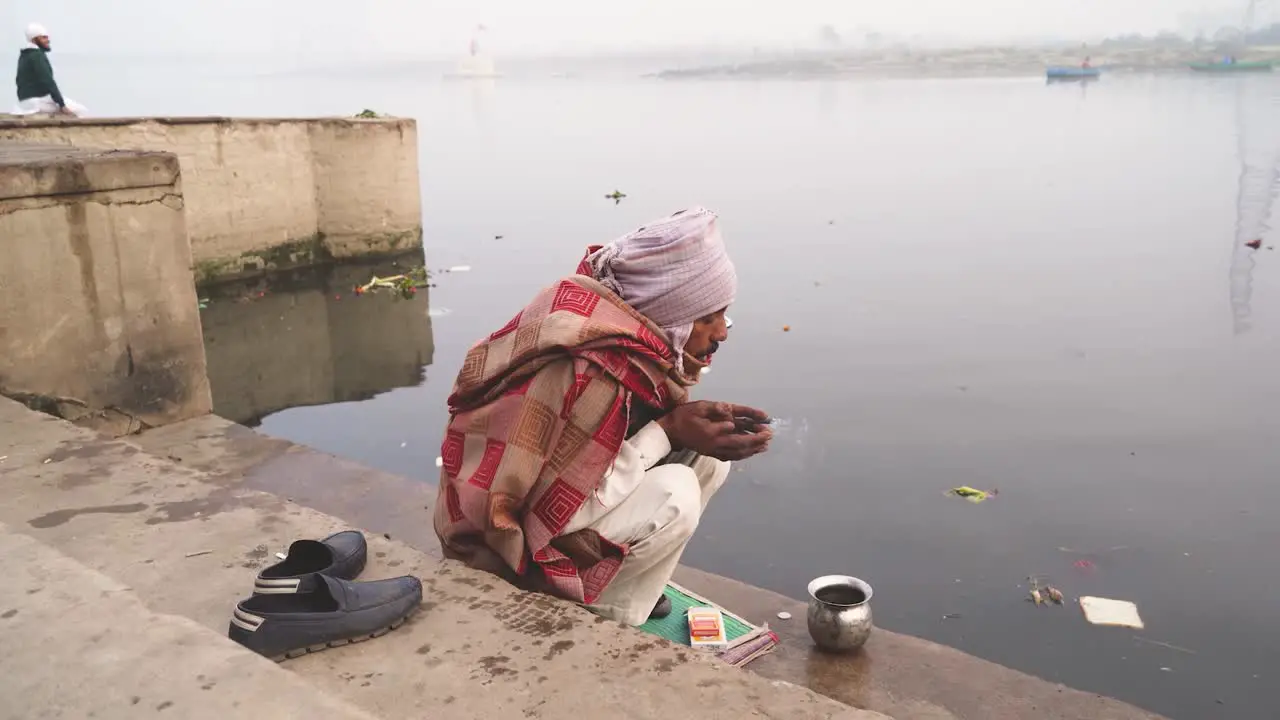 An old Hindu man offering prayers on Yamuna river ghat in Delhi India