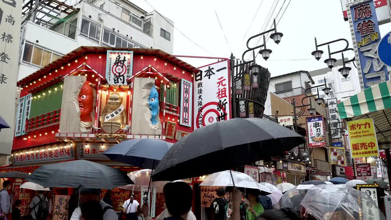 People With Umbrellas Walking Through Shinsekai Area On Rainy Day