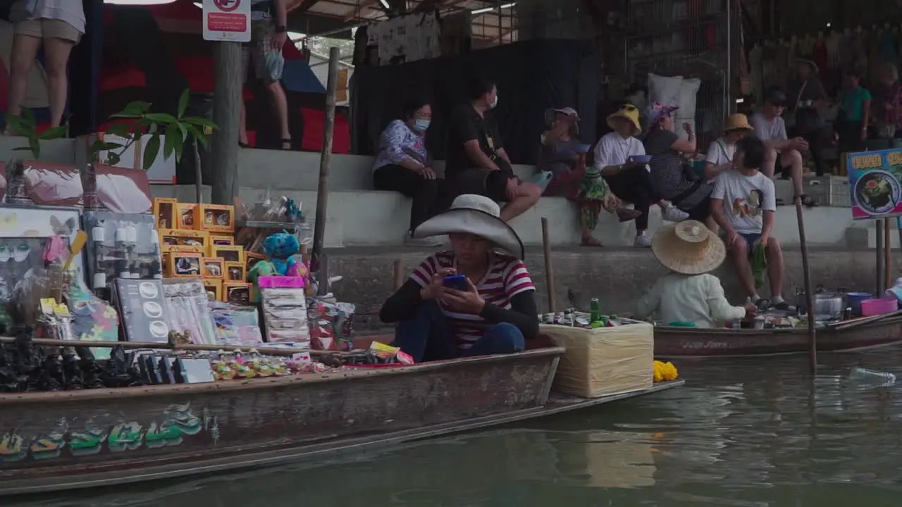 Moving forward side view Shot Scenic view of floating Market in Thailand People sitting on the steps in the background