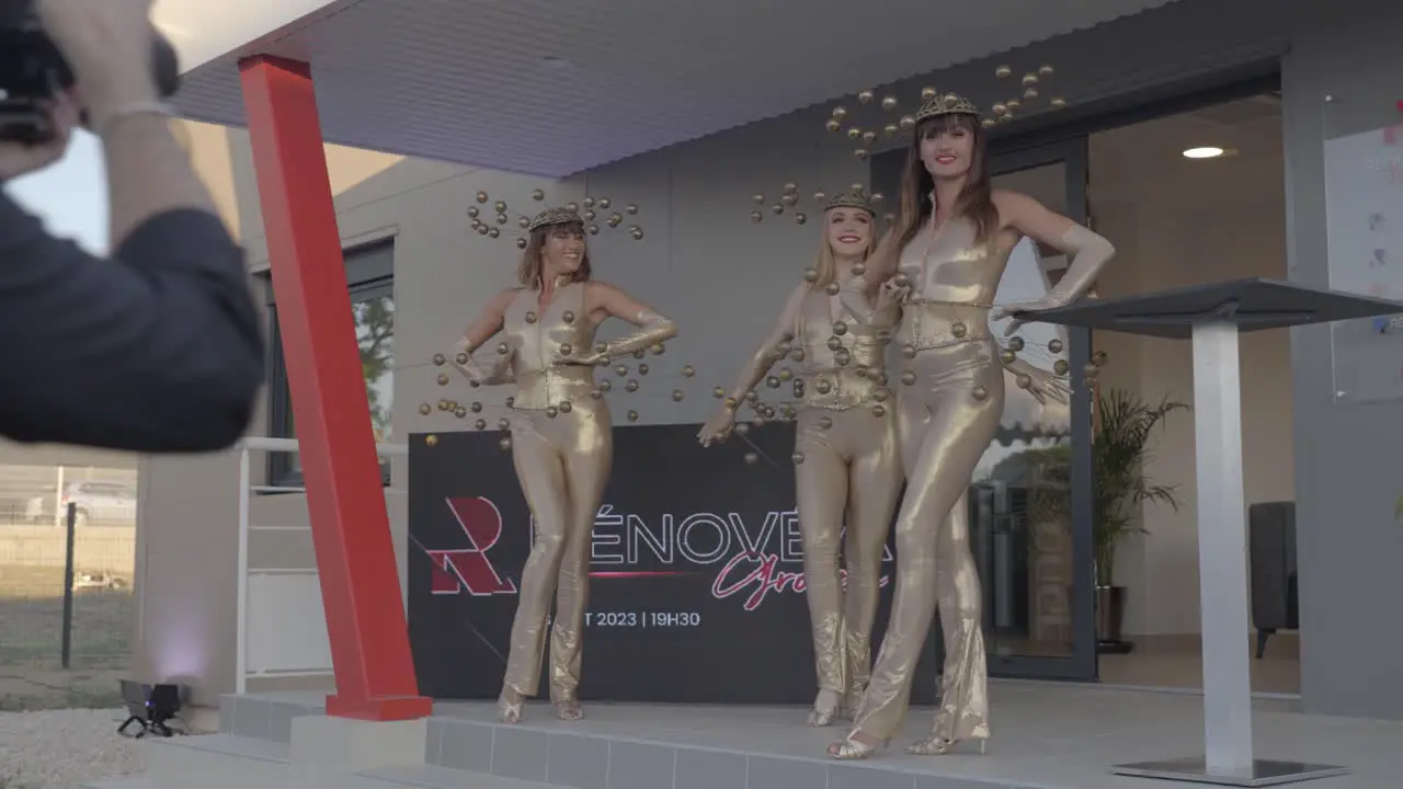 Three beautiful models in artistic costumes posing for photographer in front of business