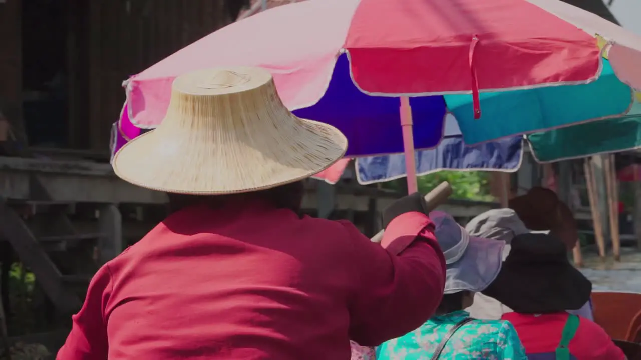 Medium shot Women in red with a straw hat rowing a tourist boat scenic view of Thailand Floating Market