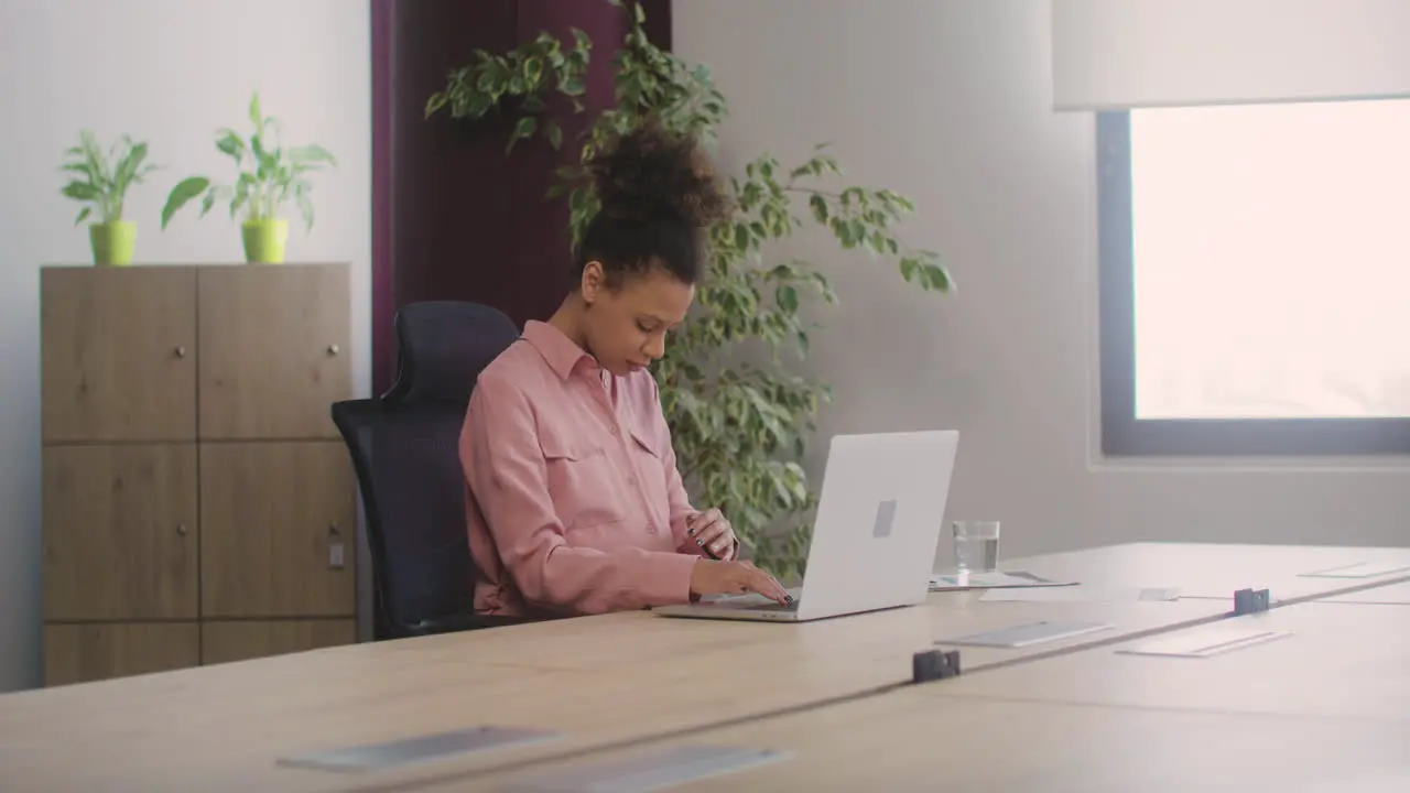 Happy Pregnant Woman Caressing Her Belly While Working In The Office