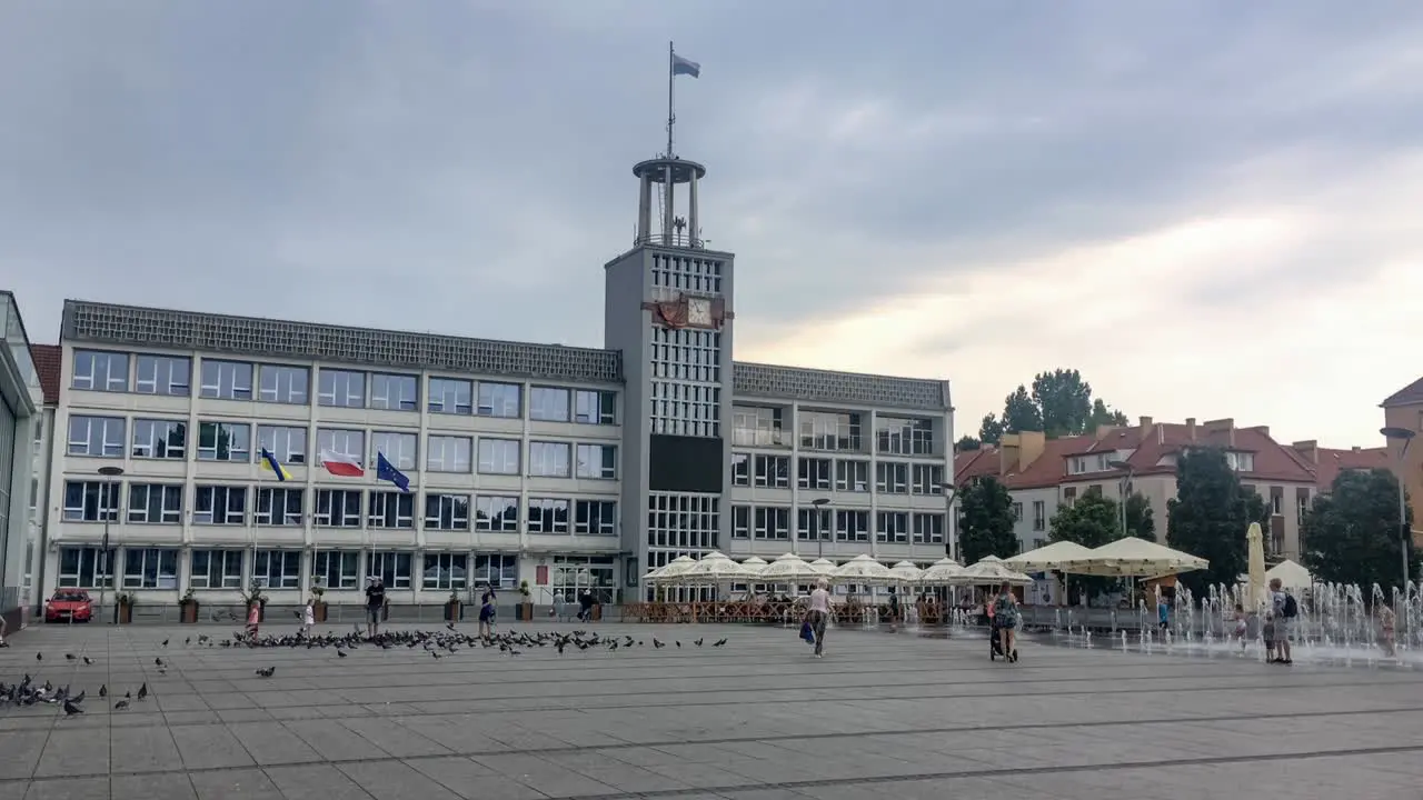 Town hall of Koszalin town in Poland in stormy weather with people playing with the fountain