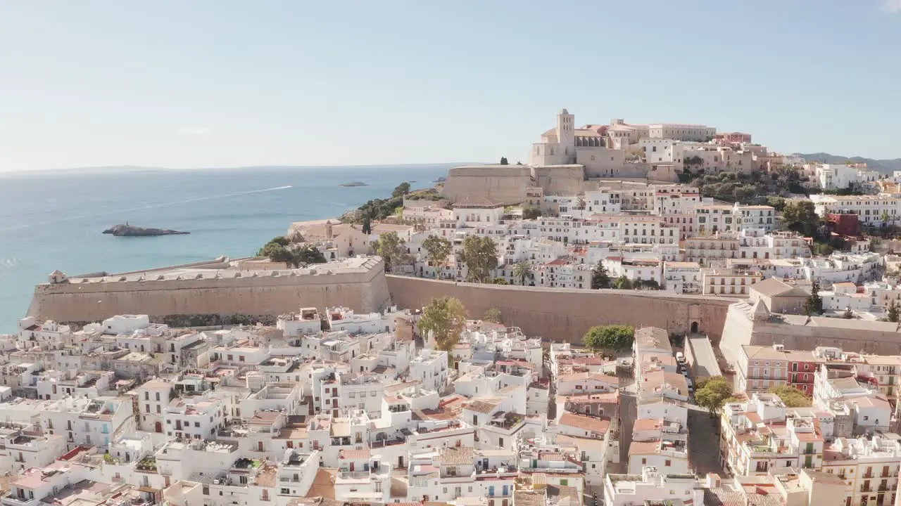 Aerial view of Ibiza city the Old Town and the city walls of Eivissa in the island of Ibiza on a sunny and clear day just after sunrise with birds flying alongside the city wall