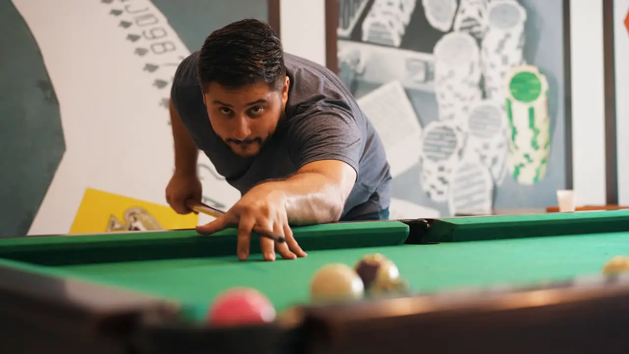 Young man playing billiard sinking a the red ball to the pocket