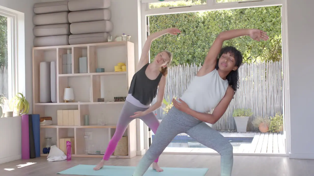 Focused diverse fitness women exercising and practicing yoga on mat in white room slow motion