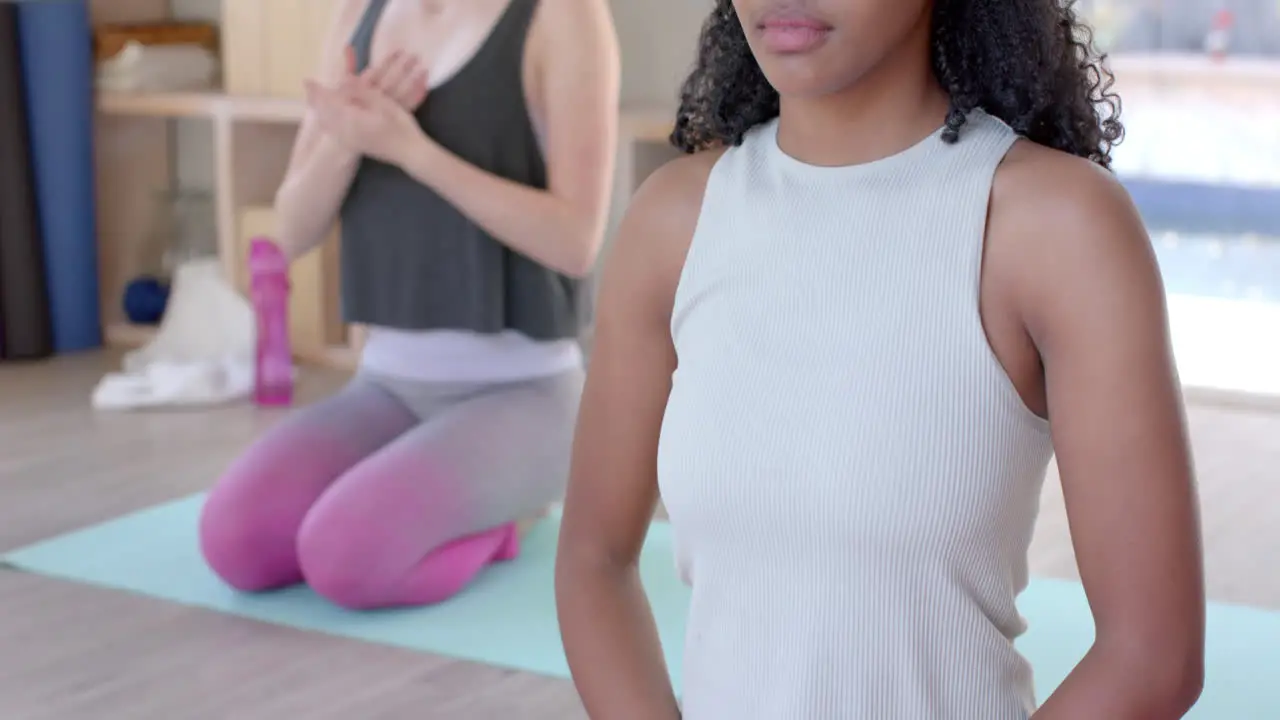 Focused diverse fitness women exercising and meditating on mat in white room slow motion