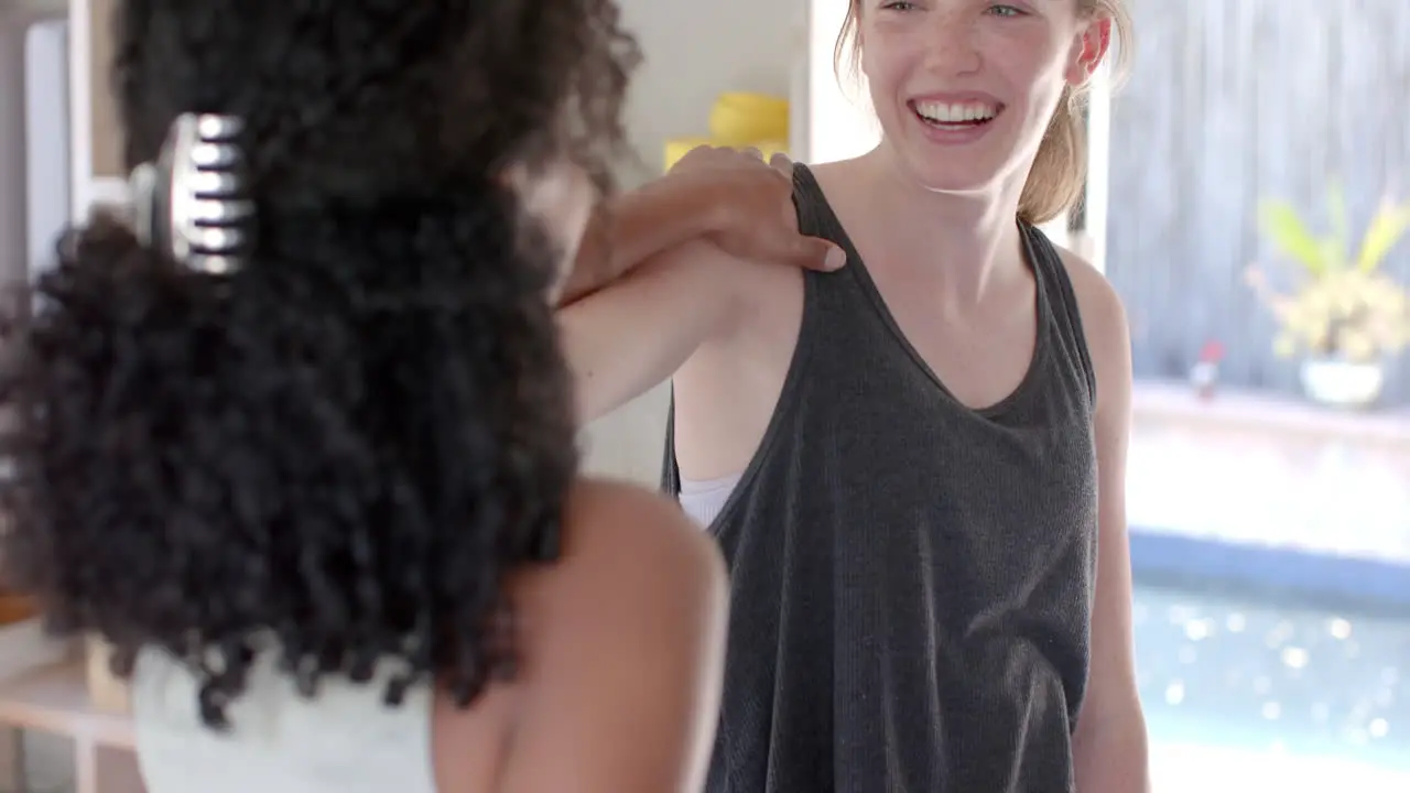 Happy diverse fitness women exercising together on mat in white room slow motion