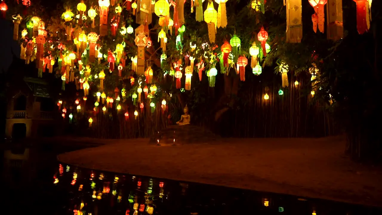 Golden Buddha statue under a tree decorated with colorful paper lamps in Chiang Mai Temple Thailand