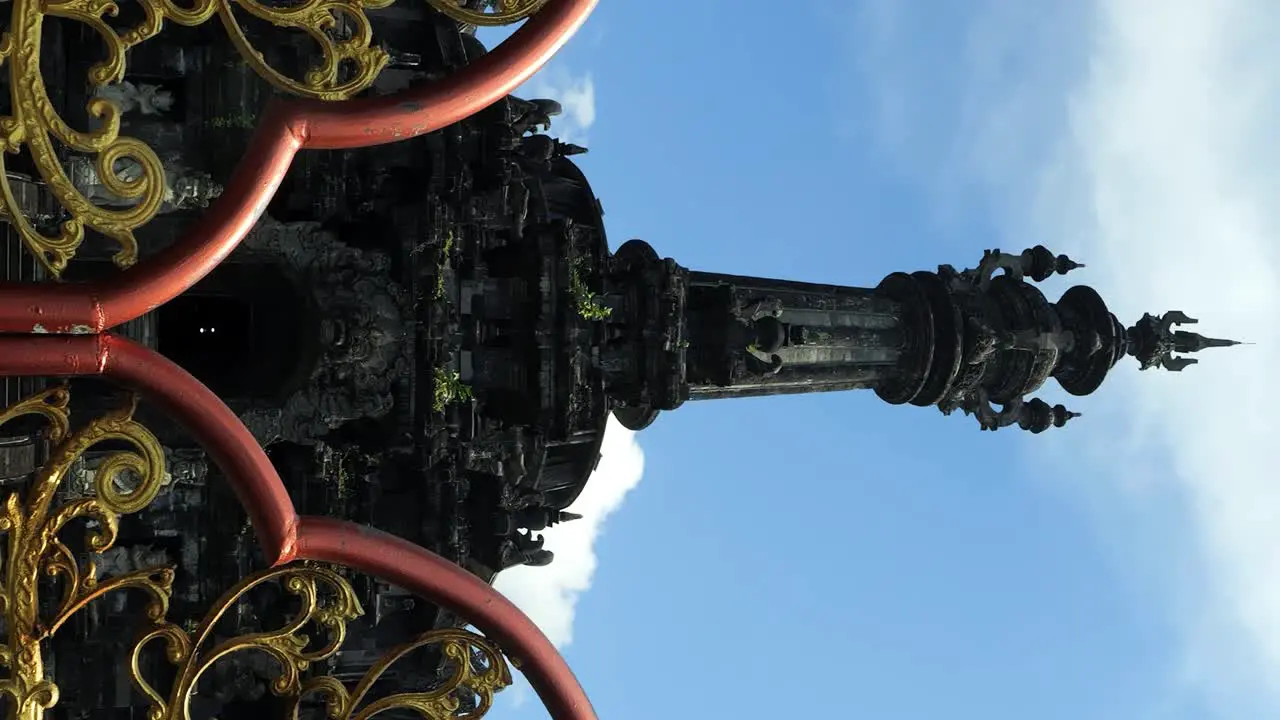 Vertical Tilt shot of a golden entrance gate opening to reveal the grand Bajra Sandhi Monument a prominent temple in Bali under the bright sunny sky