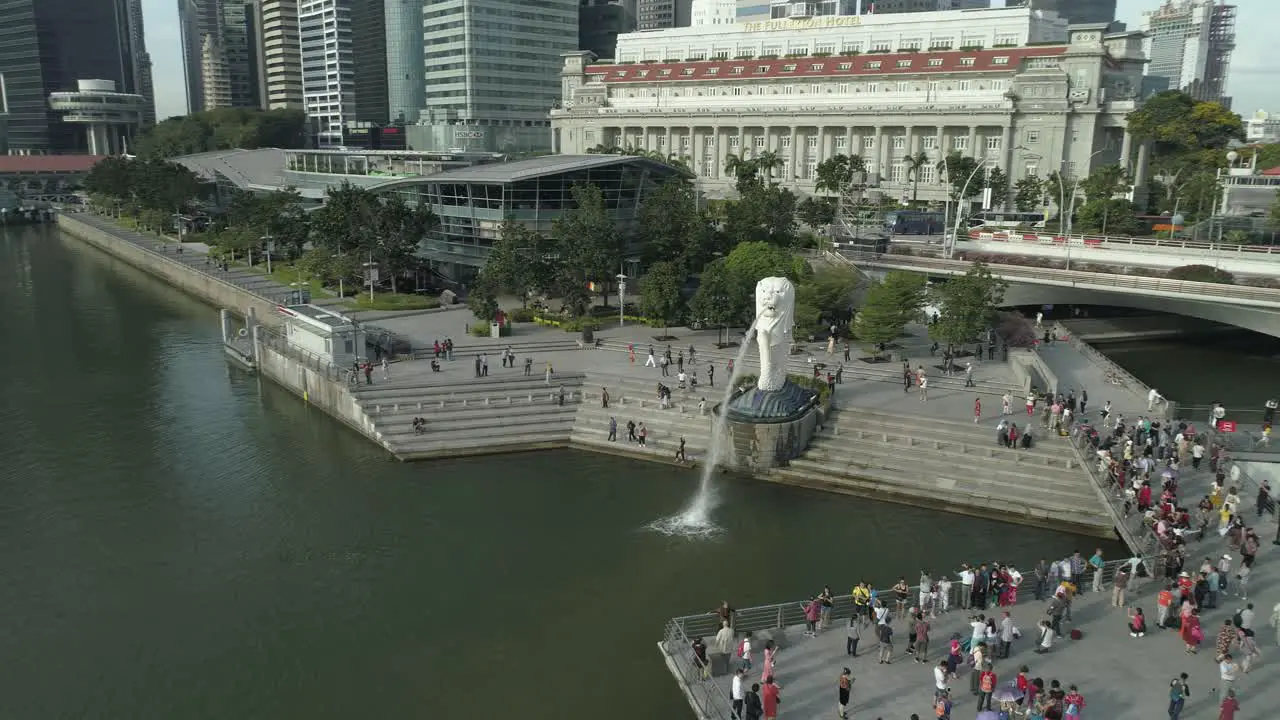 Flying around the famous merlion statue symbol of singapore surrounded by crowd of traveling tourists in the metropolis city center