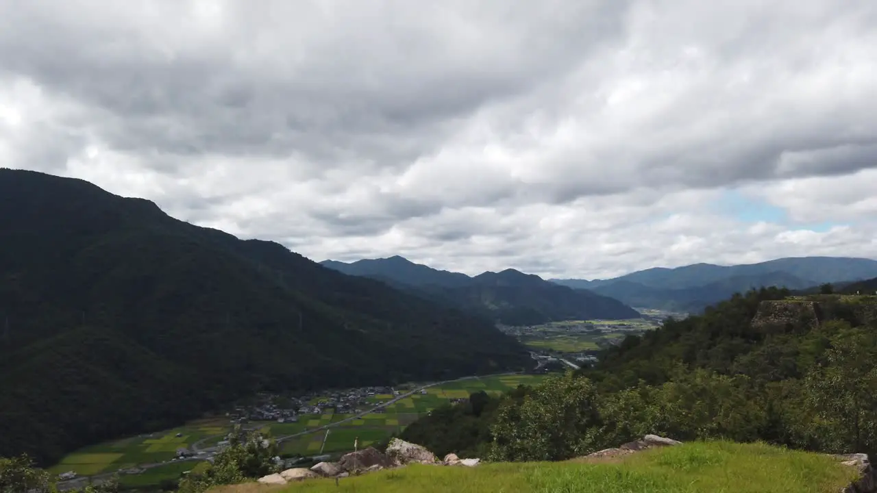 Serene pan across city of asago nestled at base of mountains by japanese ricefields