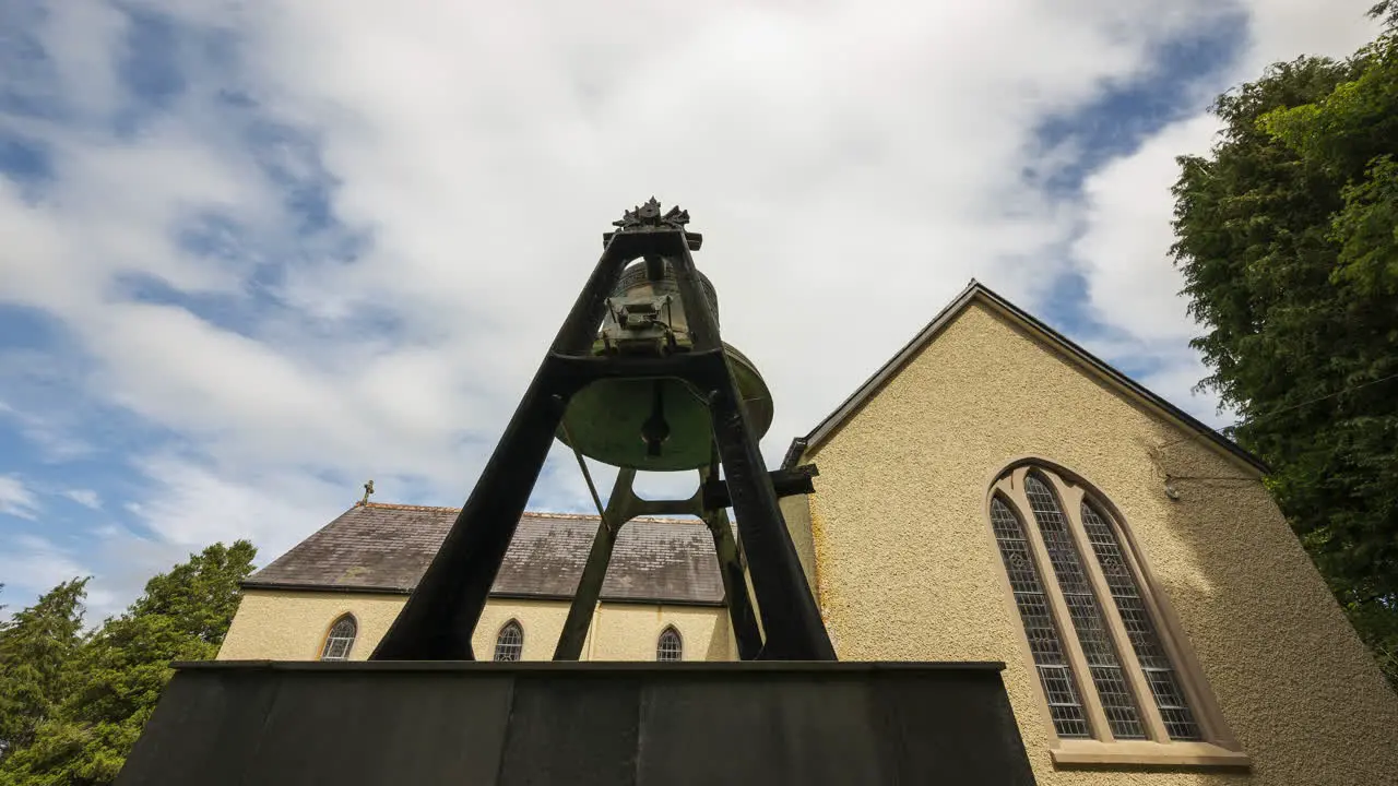 Time lapse of a historical church with large bell on a pedestal in rural countryside of Ireland during the day