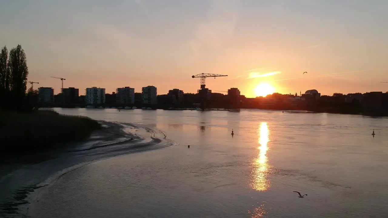 City buildings and construction cranes during golden sunset aerial fly forward