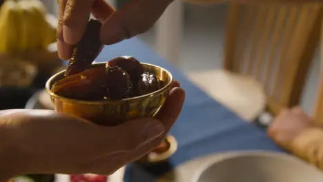 Person Offering Dates At Muslim Family Table At Home Set For Iftar Meal Breaking Daily Fast During Ramadan