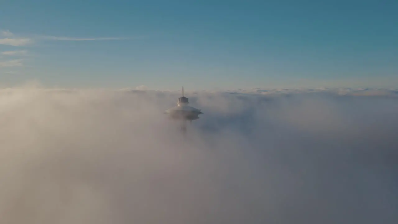 Elevator descends tall iconic structure shrouded in misty fog aerial dolly