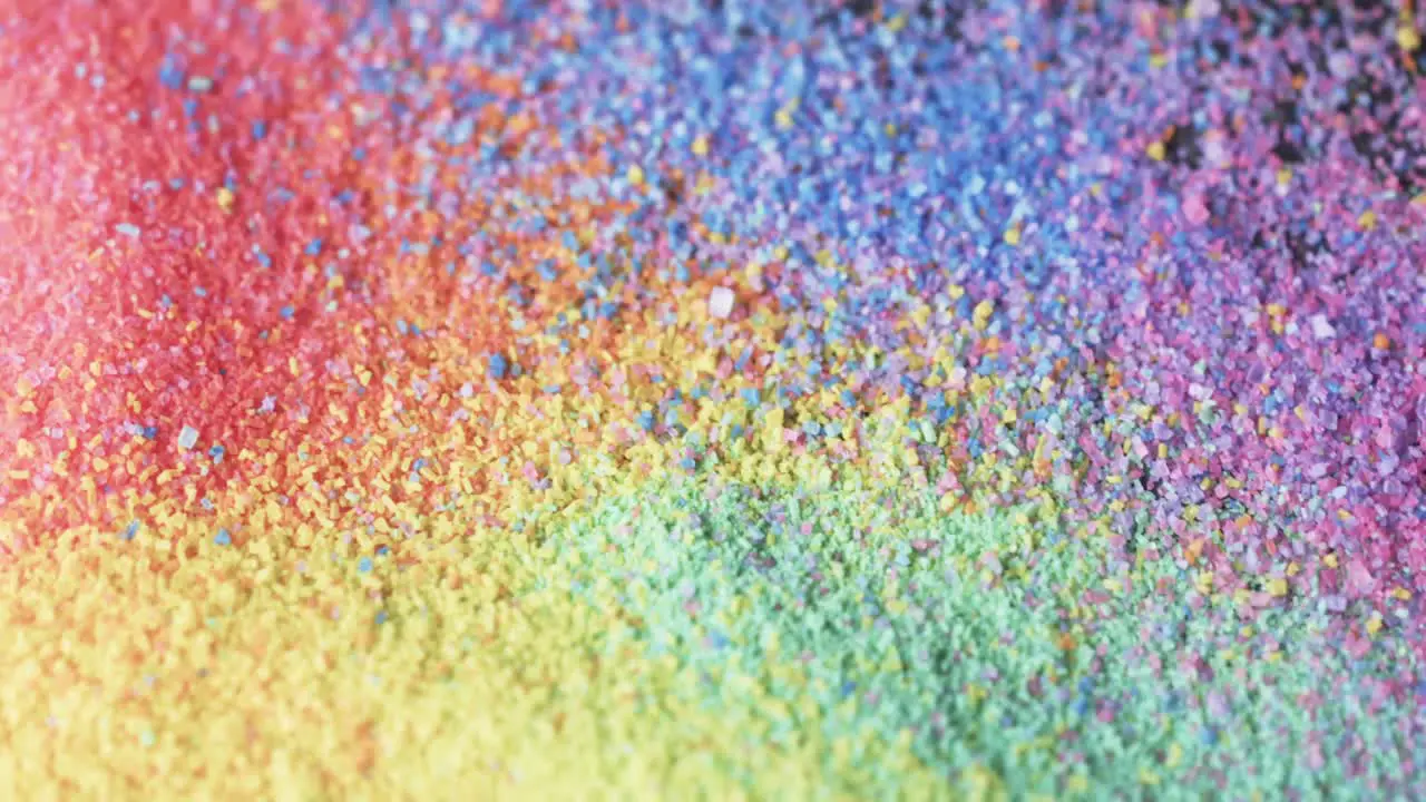 Video of close up of rainbow coloured sand grains and copy space background