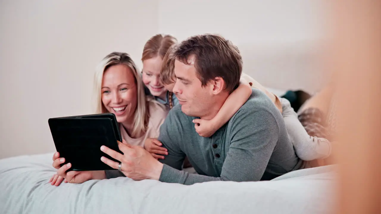 Parents children and tablet in bedroom