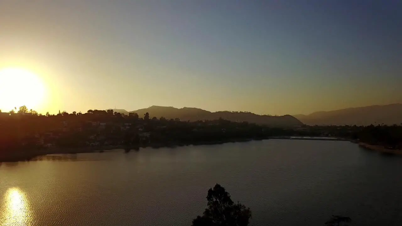 Aerial descending and panning shot of urban lake in Los Angeles during sunset