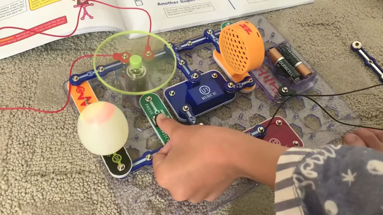 Small hands testing out the fan and colored lights button of the Snap Circuit Jr