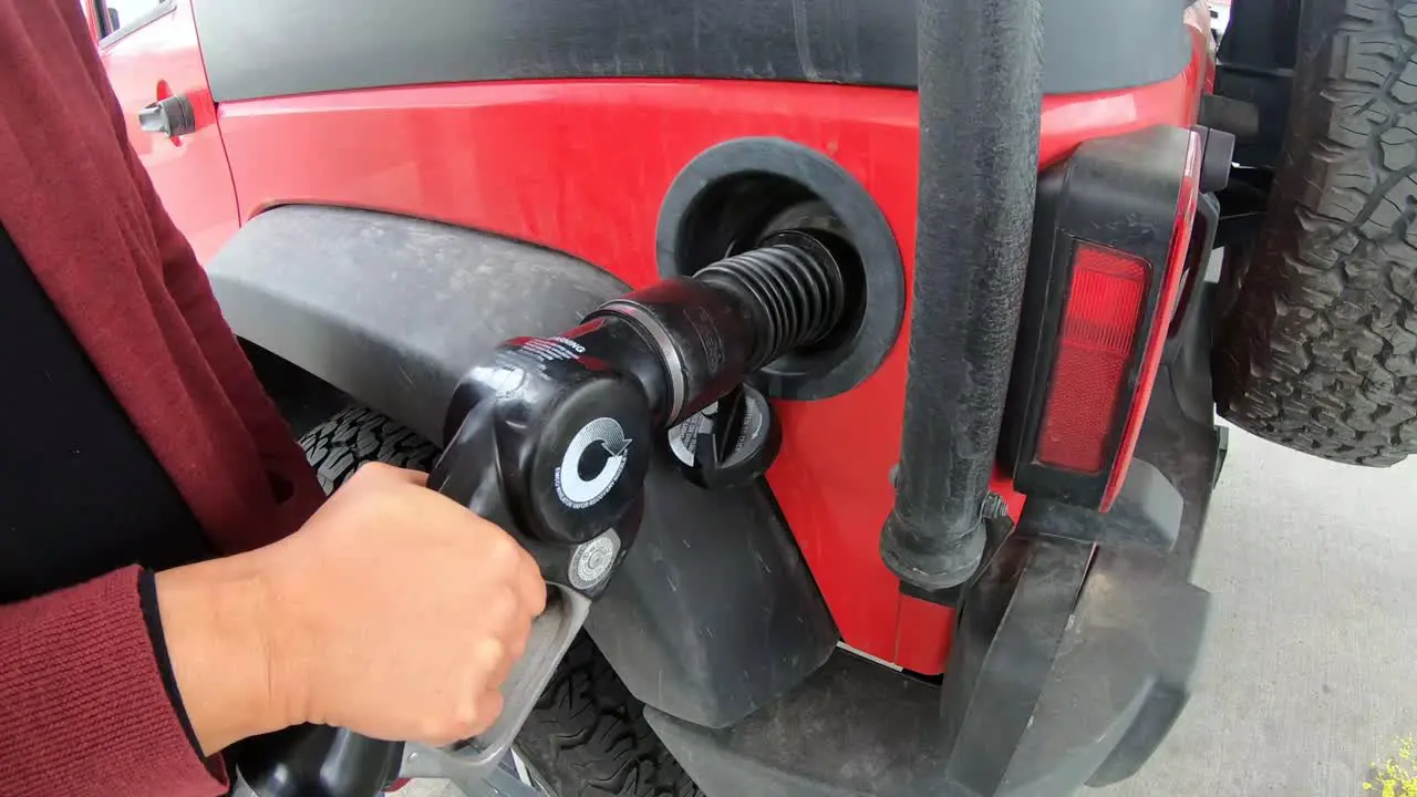 Pumping gas at gas station into red vehicle