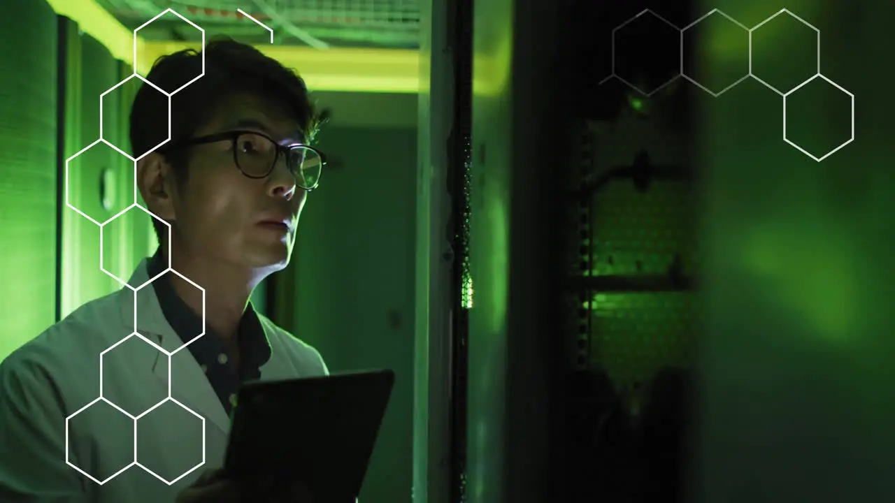 Animation of hexagons over asian male scientist working in server room