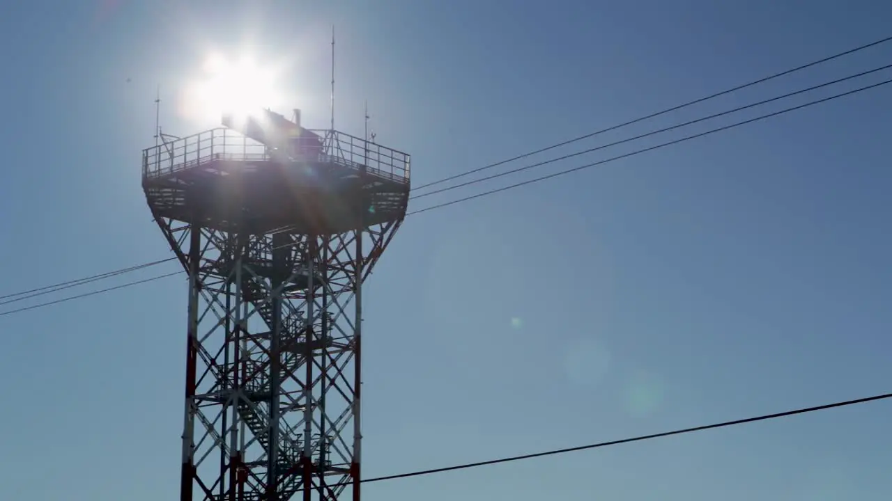 Backlit view of a communications tower against a clear blue sky in an airport in Argentina