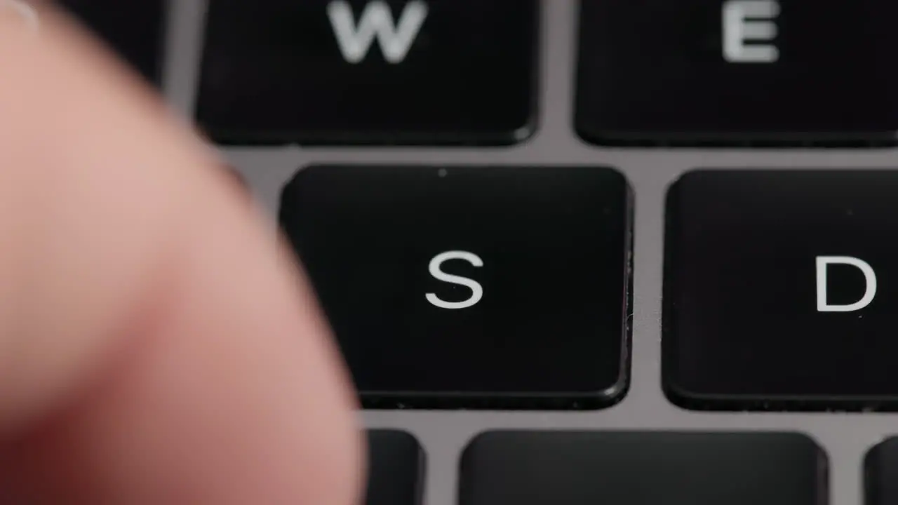 Close-up Macro Shot Of A Man Typing On A Laptop Keyboard With a Focus On The S Key