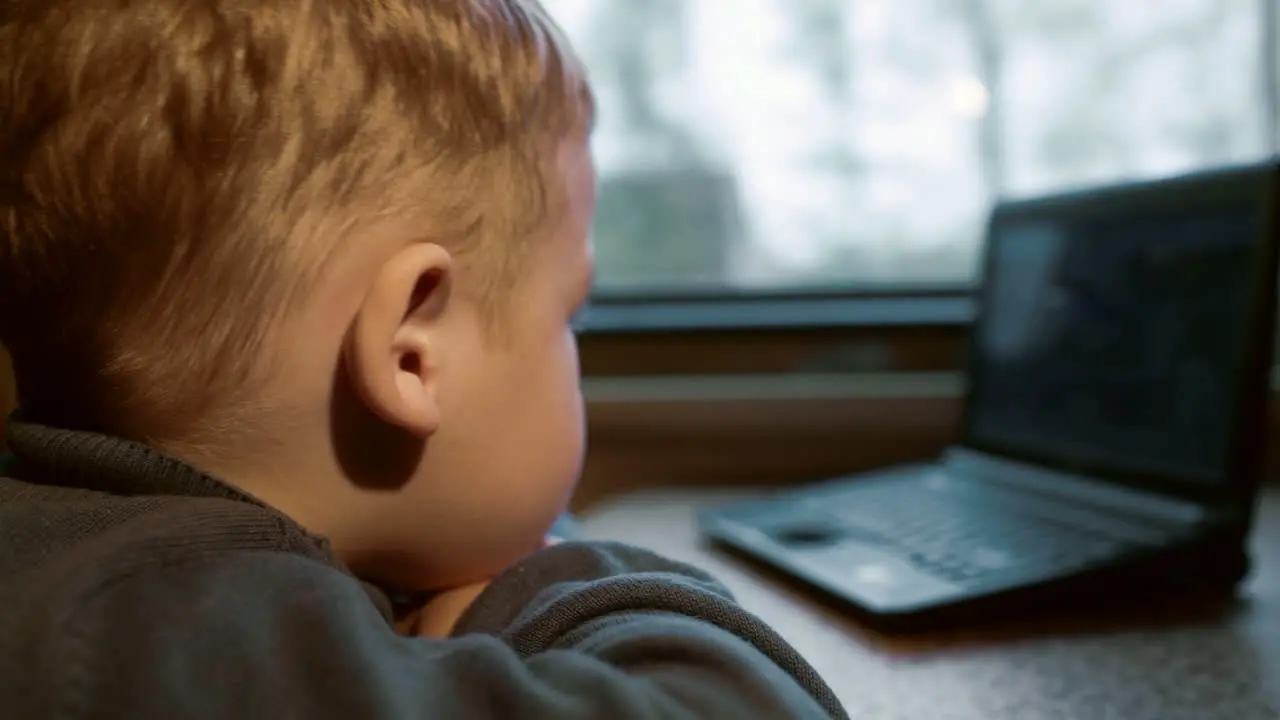 Little boy watching video on laptop in the train