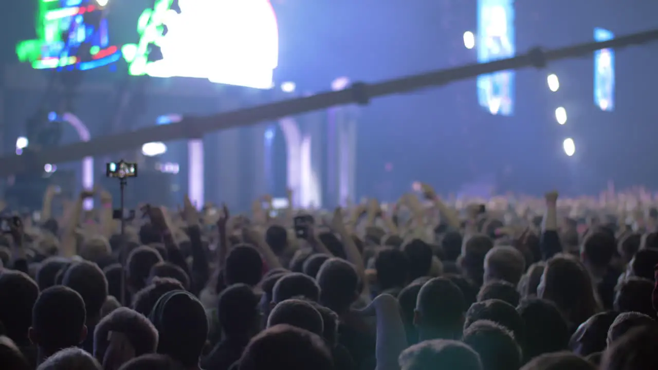 Concert audience with hands up and bright stage lights