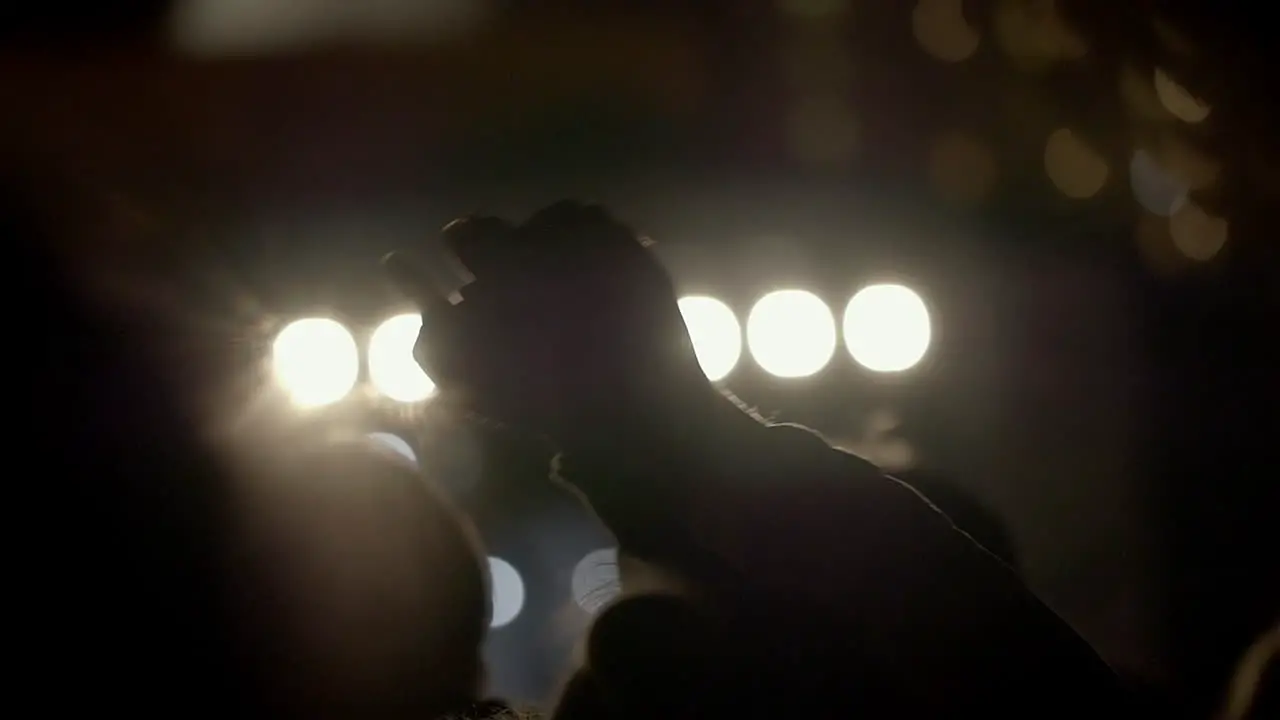 Slow motion shot from behind of swinging hands and heads at the concert