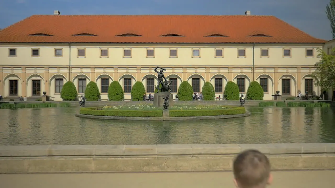 Slow motion view of small boy running to the fountain and throwing coins into the water Prague Czech Republic