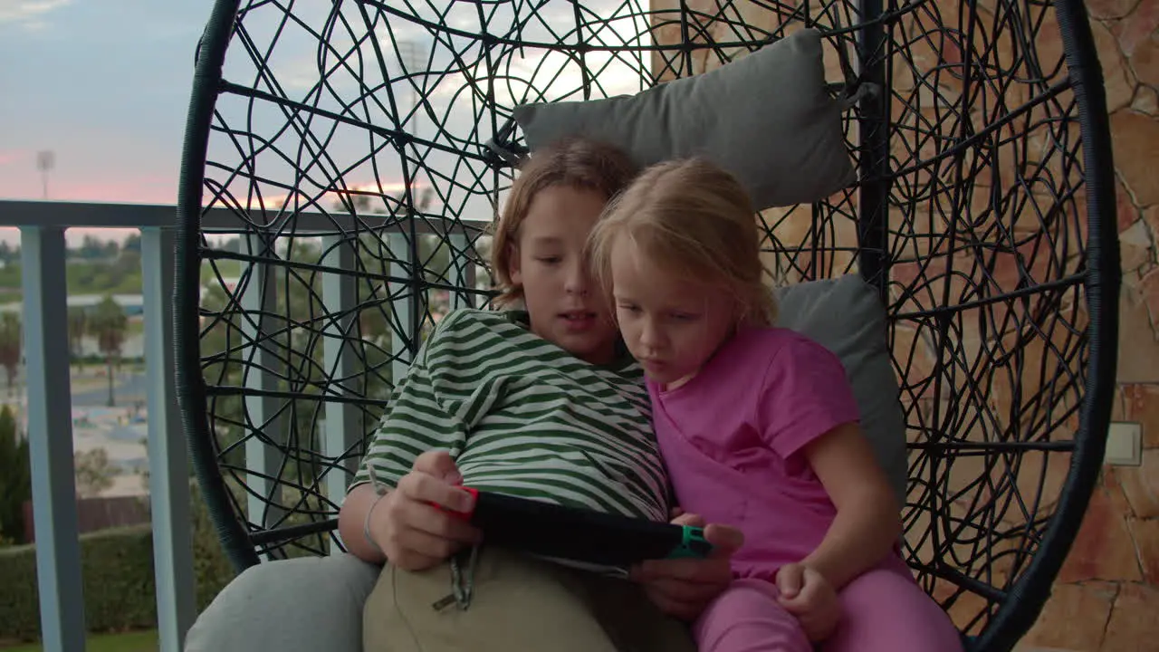 Siblings playing console on balcony