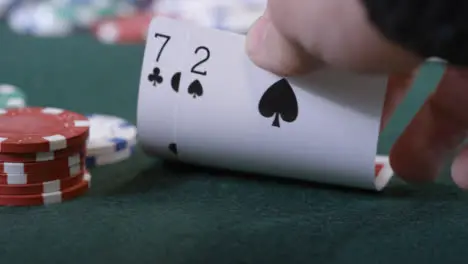 Extreme Close Up Shot of Poker Player Looking at Seven Deuce Before Folding