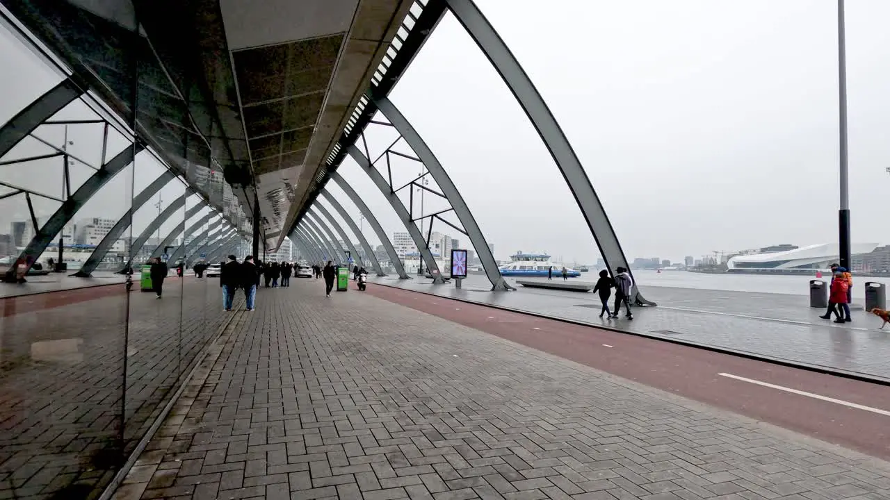 Busy bicycle lane outside of the Amsterdam Central Station Beside IJ River as people go about their day commuting on their bicycles in the busy urban city Amsterdam Netherlands