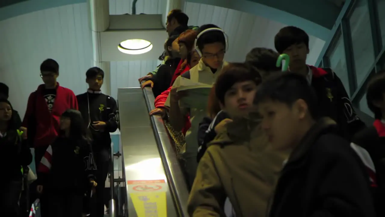 Flow of teenagers and students descending moving staircase in public transport transit