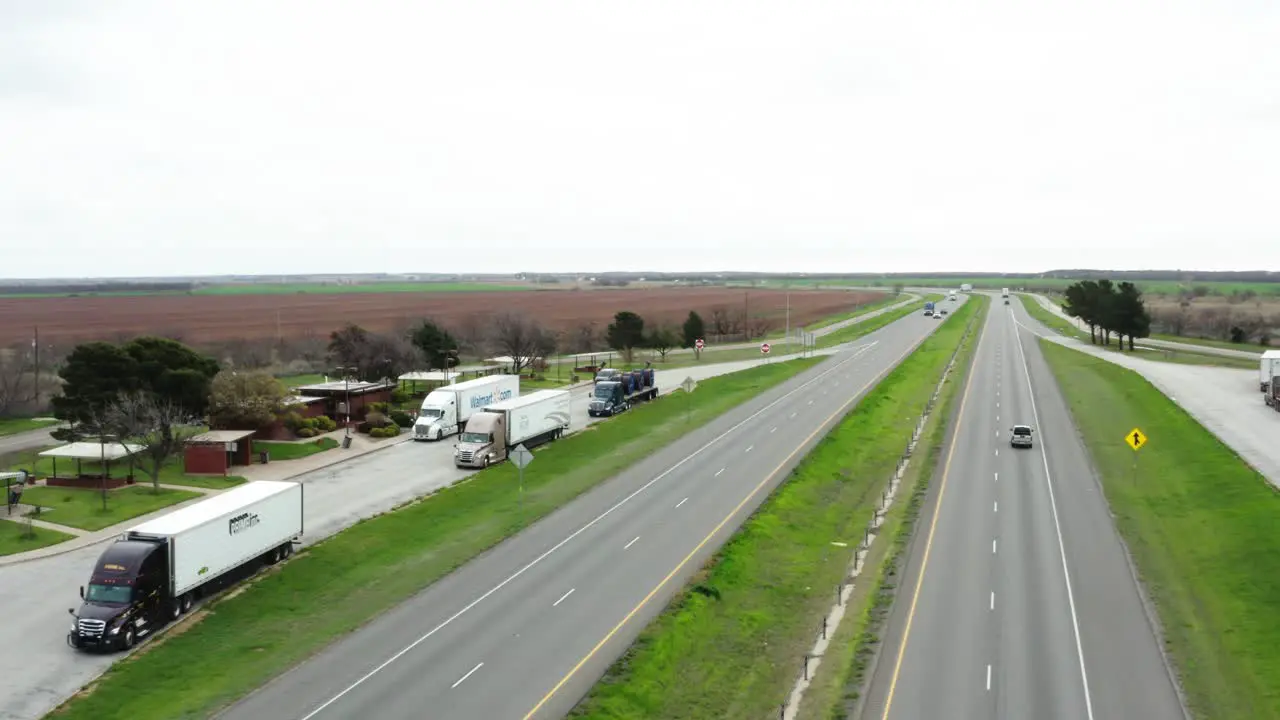 Parked semi-trucks in highway side stop in aerial orbiting view